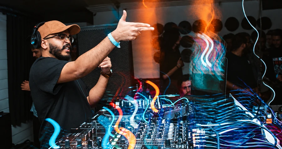 Performing a DJ set amid cyan and orange light trails